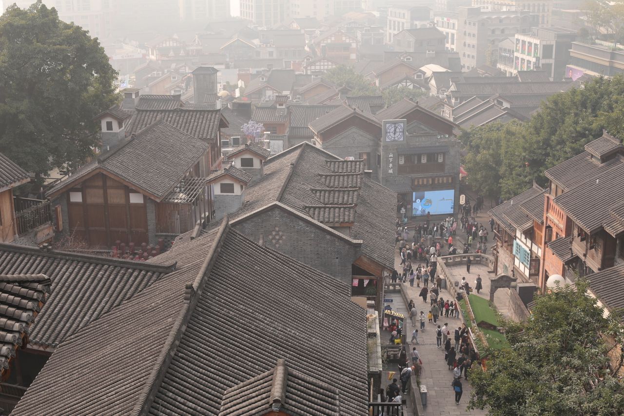 Aerial view of a bustling traditional Chinese village with historic architecture and vibrant street life.